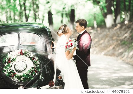 Stylish wedding couple, bride, groom kissing and hugging on retro car 44079161