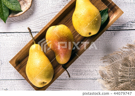 Wet yellow pears on square plate 44079747