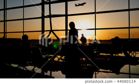 Silhouette of a tourist guy watching the take-off of the plane standing at the airport window at Silhouette of a tourist guy watching the take-off of the plane standing at the airport window at 44080114