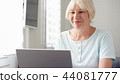 Elderly senior blond woman working on laptop computer at home. Remote freelance work on retirement 44081777