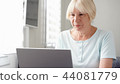 Elderly senior blond woman working on laptop computer at home. Remote freelance work on retirement 44081779