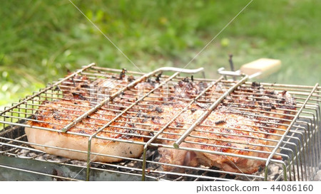 Large juicy pieces of meat are fried on the barbecue. Rest and cooking in nature. Large juicy pieces of meat are fried on the barbecue. Rest and cooking in nature. 44086160