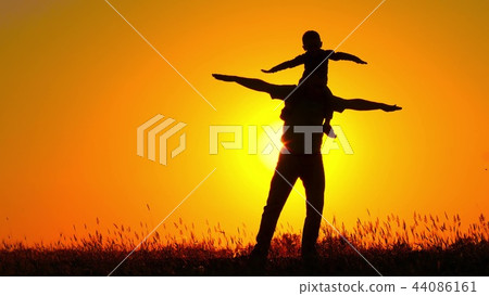 A small child spinning on his father's shoulders. Happy family playing at sunset. Silhouette. A small child spinning on his father's shoulders. Happy family playing at sunset. Silhouette. 44086161