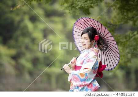 A young woman in a smiling kimono wearing a Japanese umbrella against the backdrop of Kashi-Arashiyama, Ukyo-ku, Kyoto, Kyoto Prefecture A young woman in a smiling kimono wearing a Japanese umbrella against the backdrop of Kashi-Arashiyama, Ukyo-ku, Kyoto, Kyoto Prefecture 44092187