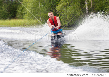 Young athletic man riding kneeboard on a lake Young athletic man riding kneeboard on a lake 44092616