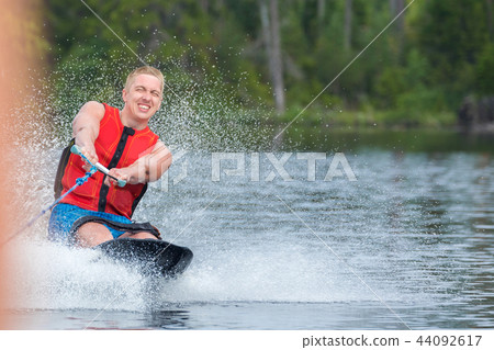 Young athletic man riding kneeboard on a lake 44092617