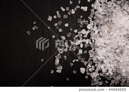 White diamond coarse grain salt heap on black stone background. 44094608