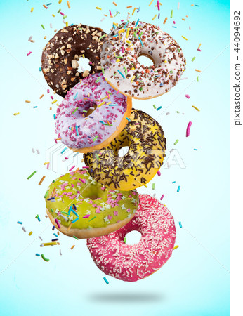 Tasty doughnuts in motion falling on pastel blue background. 44094692
