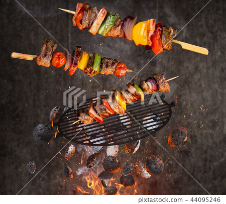 Hot briquettes, cast iron grate and tasty skewers flying in the air. Hot briquettes, cast iron grate and tasty skewers flying in the air. 44095246
