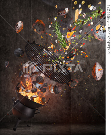 Kettle grill with hot briquettes, cost iron grid and spices flying in the air. 44095275