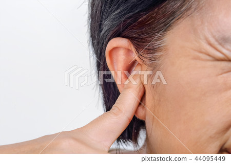 Senior woman closes ear to protect from loud noise Senior woman closes ear to protect from loud noise 44095449
