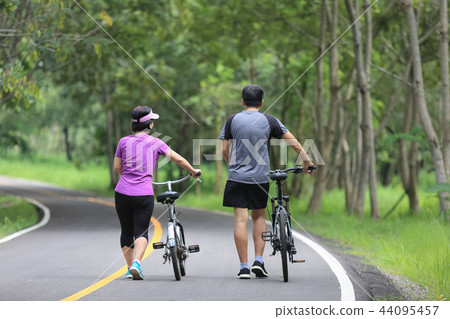 Middle aged couple walking with their bicycle Middle aged couple walking with their bicycle 44095457