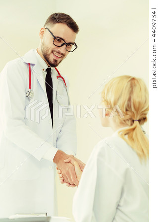 Doctor at hospital shakes hand with another doctor Doctor at hospital shakes hand with another doctor 44097341