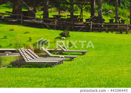 Row of wooden sunchairs in garden Row of wooden sunchairs in garden 44106445