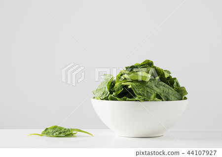 raw spinach leaves in a white bowl 44107927