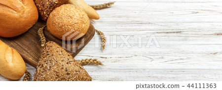 Bread and wheat on white wooden background. 44111363