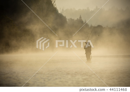 Fisherman holding fishing rod, standing in river 44111468