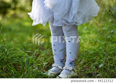 The legs of a little girl in a white dress The legs of a little girl in a white dress 44112312