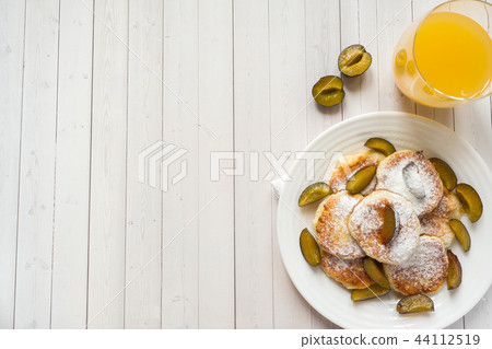 Cheese pancakes in powdered sugar with fresh plums Cheese pancakes in powdered sugar with fresh plums 44112519