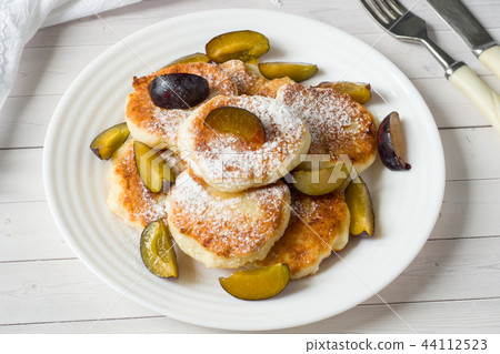 Cheese pancakes in powdered sugar with fresh plums 44112523