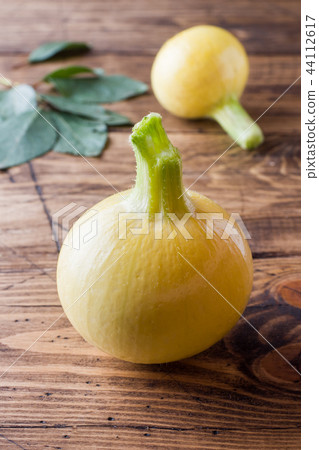 Small yellow pumpkin squash on a wooden table. Small yellow pumpkin squash on a wooden table. 44112617