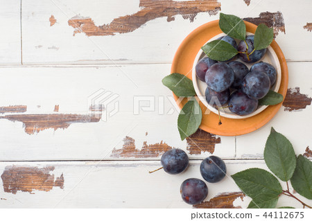Fresh plum berries on a plate with leaves Fresh plum berries on a plate with leaves 44112675