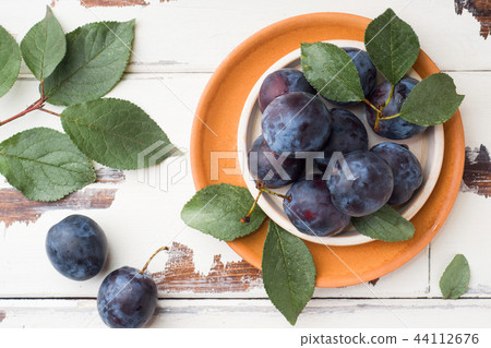 Fresh plum berries on a plate with leaves  44112676