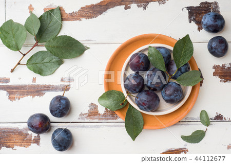 Fresh plum berries on a plate with leaves  44112677