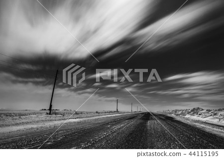 Empty freeway at night. Black and white. Road to the horizon. Clouds, rapidly running across the sky 44115195