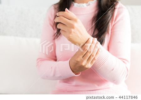Woman sitting on sofa holds her wrist hand injury 44117846