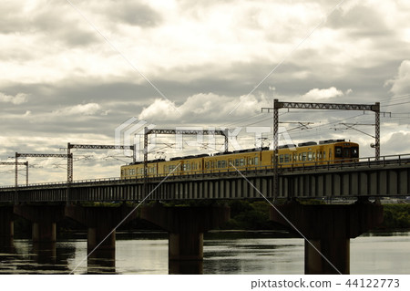 Yellow train crossing an iron bridge 44122773