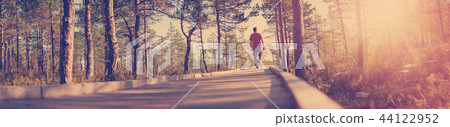 Man walking on wooden walkway in nature Man walking on wooden walkway in nature 44122952