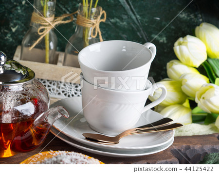 Hot tea in glass tea pot and white cups Hot tea in glass tea pot and white cups 44125422