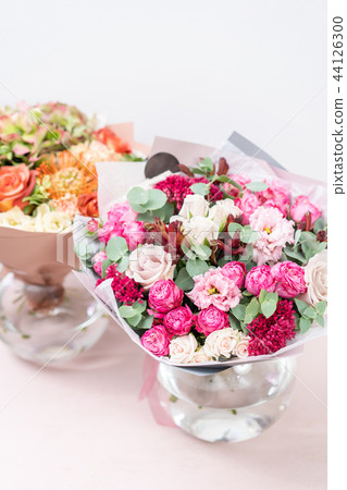 two beautiful spring bouquet. flowers arrangements with various of colors in glass vase on pink 44126300