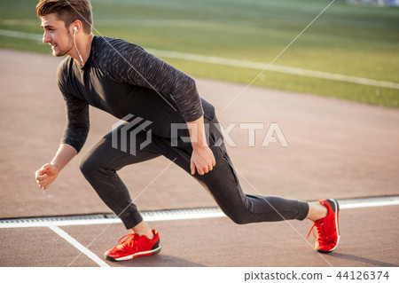 athlete in black clothes starting sprint on running track athlete in black clothes starting sprint on running track 44126374