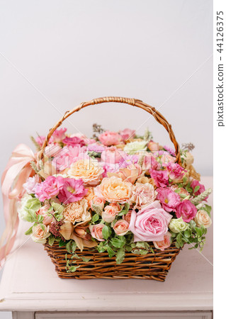 flowers arrangement with various of colors in wicker basket on pink table. beautiful spring bouquet flowers arrangement with various of colors in wicker basket on pink table. beautiful spring bouquet 44126375
