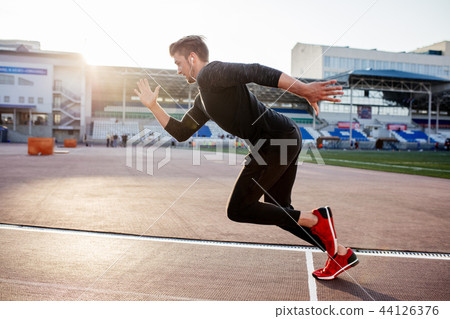 athlete in black clothes starting sprint on running track athlete in black clothes starting sprint on running track 44126376