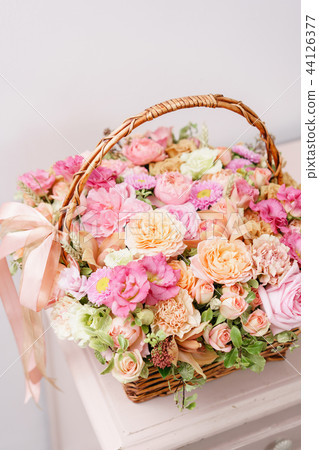 flowers arrangement with various of colors in wicker basket on pink table. beautiful spring bouquet flowers arrangement with various of colors in wicker basket on pink table. beautiful spring bouquet 44126377