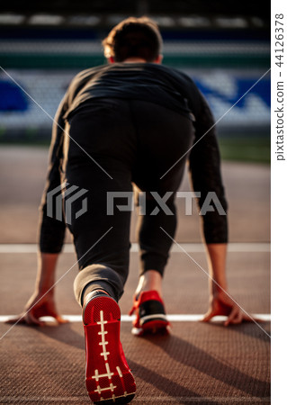 man feet in starting position for running on race track in stadium man feet in starting position for running on race track in stadium 44126378