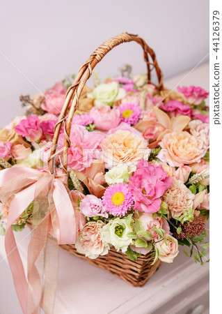 flowers arrangement with various of colors in wicker basket on pink table. beautiful spring bouquet 44126379