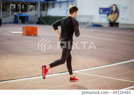 male athlete wearing black sportwear running at track, side view 44126465