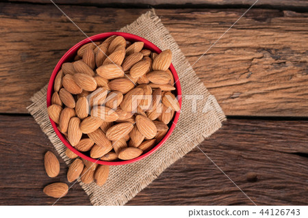 Almond nut in a ceramic bowl against wooden table 44126743
