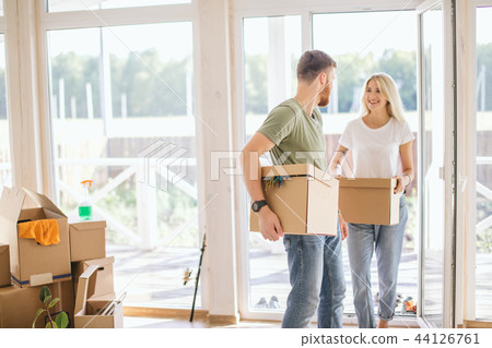 Happy Couple Carrying Cardboard Boxes Into New Home On Moving Day 44126761