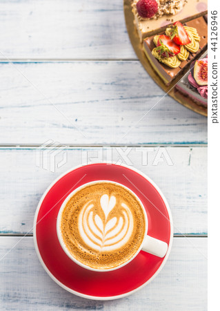 A cup of art coffee cappiciino and mini raw cakes A cup of art coffee cappiciino and mini raw cakes 44126946