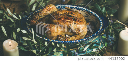 Whole roasted chicken with garlic decorated with olive tree branch 44132902