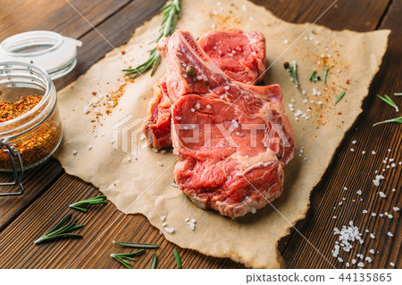 Uncooked meat in seasoning on wooden table Uncooked meat in seasoning on wooden table 44135865