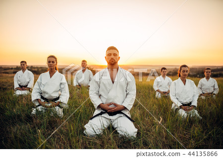 Karate group sitting on the ground and meditates Karate group sitting on the ground and meditates 44135866