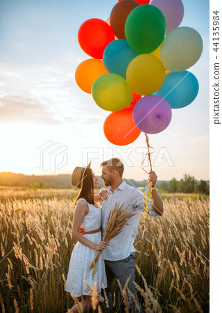 Couple holds balloons and kissing in wheat field Couple holds balloons and kissing in wheat field 44135984