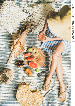Picnic concept with woman in dress, wine, fruits and baguette Picnic concept with woman in dress, wine, fruits and baguette 44137975