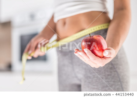 Woman holding red apple and measure tape. Woman holding red apple and measure tape. 44153440